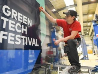 Eine Person klebt einen Greentech-Festival-Werbeaufkleber auf eine Lokomotive der Deutschen Bahn